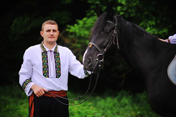 Молодий хлопчик на національній сукні з конем — стокове фото