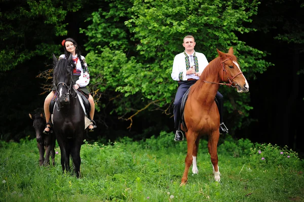 Casal jovem em vestido nacional com cavalos — Fotografia de Stock