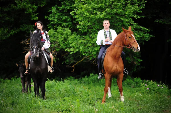 Mladý pár v národních krojích s koňmi — Stock fotografie