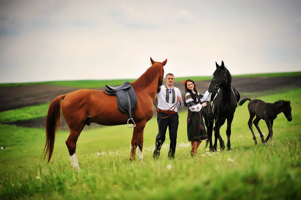 Mladý pár v národních krojích s koňmi — Stock fotografie