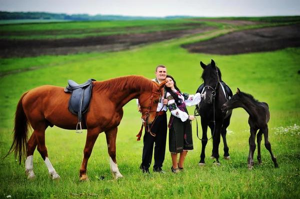 Young couple on national dress with horses — Stock Photo, Image