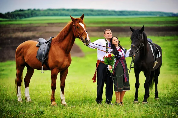 Mladý pár v národních krojích s koňmi — Stock fotografie