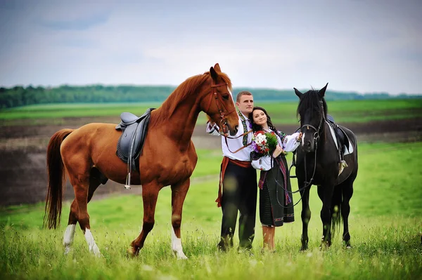 Casal jovem em vestido nacional com cavalos — Fotografia de Stock