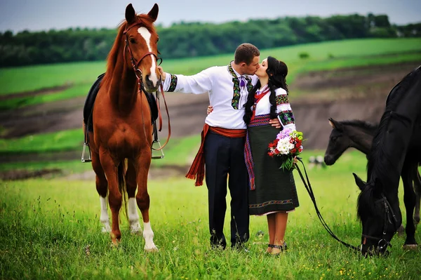 Молодая пара в национальной одежде с лошадьми — стоковое фото
