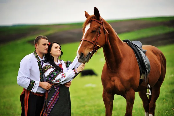 Ungt par på nationella klänning med hästar — Stockfoto