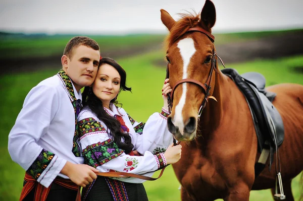 Mladý pár v národních krojích s koňmi — Stock fotografie