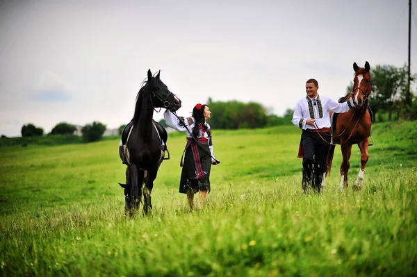 Young couple on national dress with horses — Stock Photo, Image