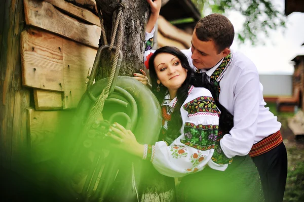 Jeune couple en robe nationale près de vieux trombone — Photo