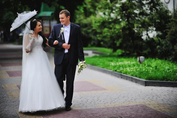 Bröllopsparet på bakgrunden bron under paraply — Stockfoto