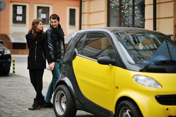 Young beautiful stylish couple stay near yellow city car — Stock Photo, Image