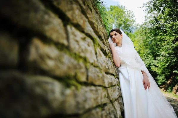 Joven novia estancia cerca de muro de piedra — Foto de Stock