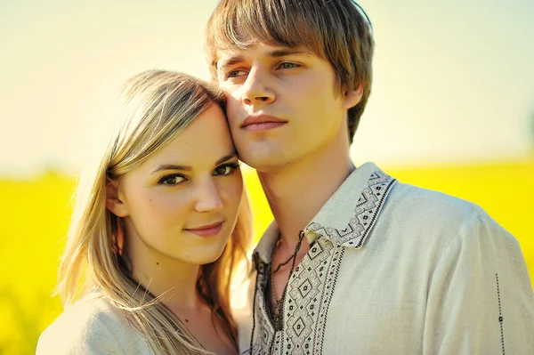 Couple on traditional dress at yellow flowers field — Stock Photo, Image