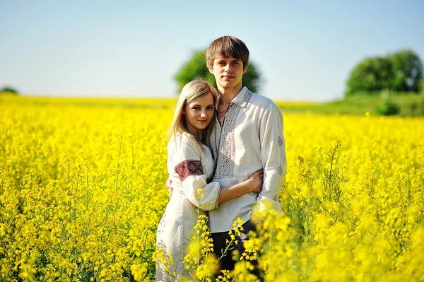 Couple on traditional dress at yellow flowers field — Stock Photo, Image