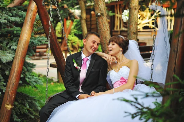 Νύφη και γαμπρός χαμόγελο σε μια κούνια την ημέρα του γάμου τους — Φωτογραφία Αρχείου