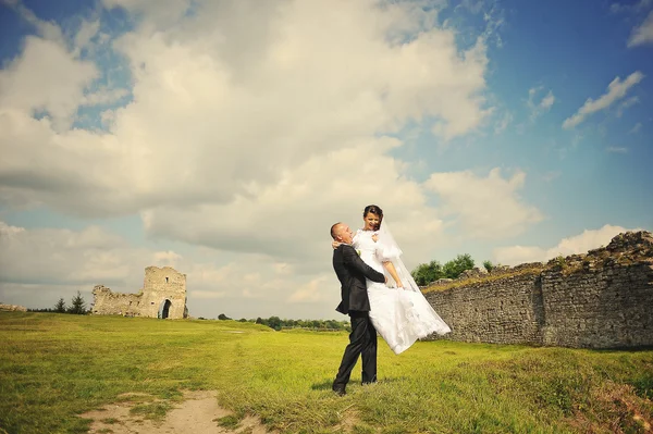 Marié prendre sa mariée aux mains backqround ciel bleu et mur o — Photo