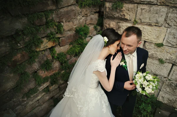 Nowożeńcy zatrzymać w pobliżu stary kamienny mur — Zdjęcie stockowe