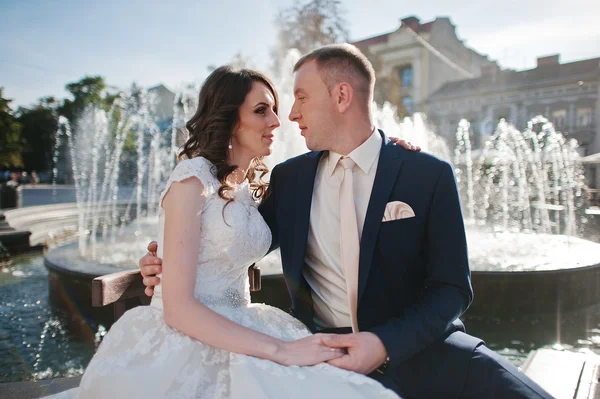 Walking couple sitting near fountain — Stock Photo, Image