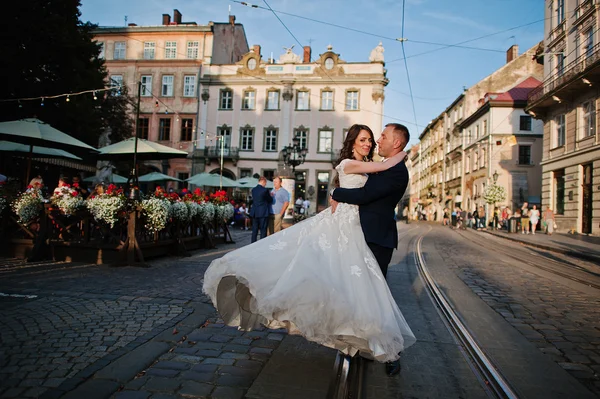 Groom tenant sur les mains sa mariée sur fond vieille ville — Photo