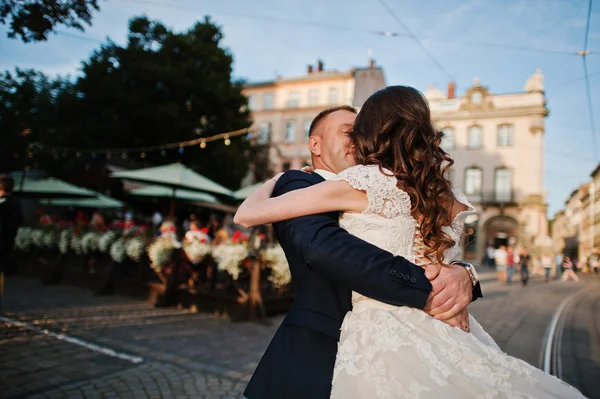 Mirele ține pe mâini mireasa lui pe fundal oraș vechi — Fotografie, imagine de stoc