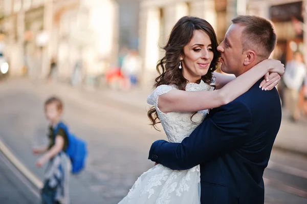 Groom tenant sur les mains sa mariée sur fond vieille ville — Photo