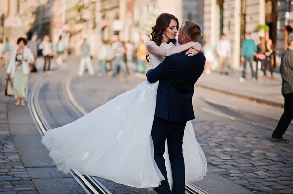 Bräutigam hält seine Braut im Hintergrund der Altstadt an den Händen — Stockfoto