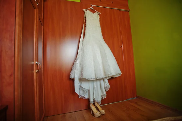 Белое свадебное платье на вешалке с туфлями — стоковое фото