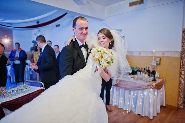 Bruidegom bedrijf bruid op handen in het restaurant — Stockfoto