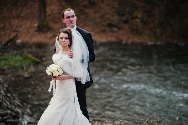 Adorável recém-casados fundo cachoeira no frio dia de outono — Fotografia de Stock