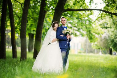 Genç güzel ve parkta yürüyüş çarklı Düğün çifti