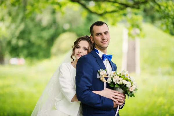 Junges schönes und fröhliches Hochzeitspaar spaziert durch den Park — Stockfoto