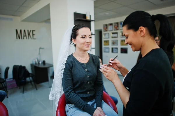 Maquiagem artista fazendo maquiagem para jovem bela noiva morena — Fotografia de Stock