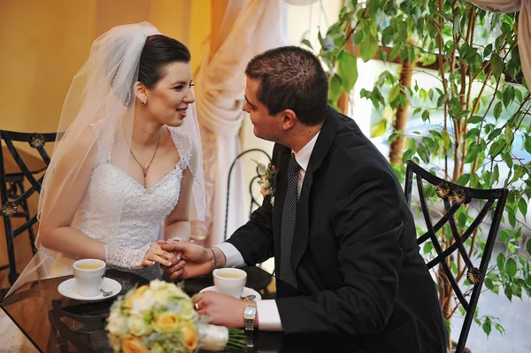 Recién casados felices y sonrientes sentados en una mesa en un café — Foto de Stock