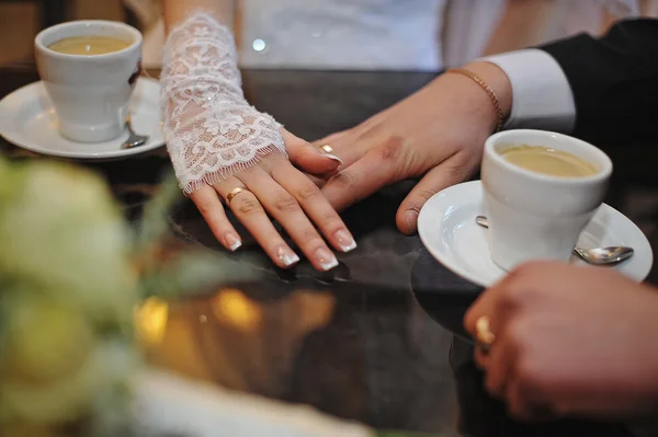 Las manos de la pareja de boda con anillos y taza de café —  Fotos de Stock