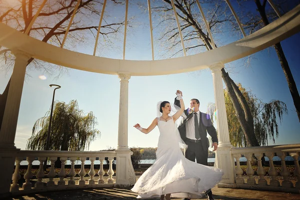 Beau couple juste marié sous arc blanc sur le soleil — Photo