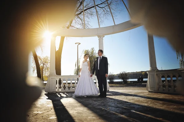 Beau couple juste marié sous arc blanc sur le soleil — Photo