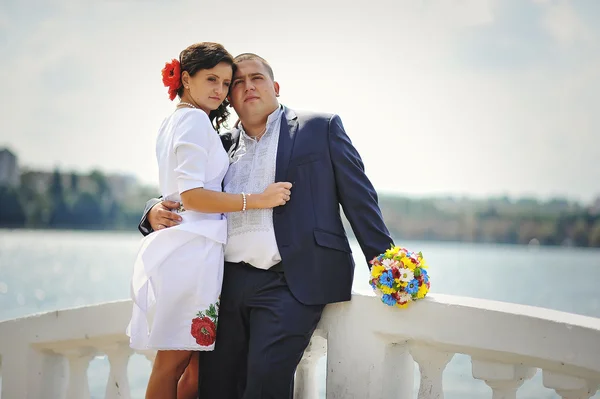 Couple on traditional dress at white stone bridge near lake — Stock Photo, Image