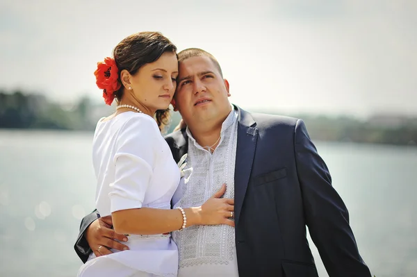 Couple on traditional dress at white stone bridge near lake — Stock Photo, Image