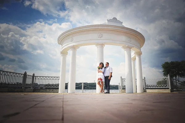 Pareja en vestido tradicional cerca del arco con cielo nublado — Foto de Stock