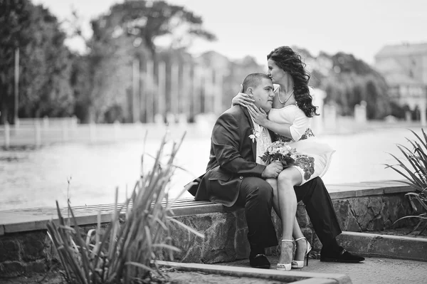 Pareja en vestido tradicional sentado y abrazar el lago de fondo — Foto de Stock