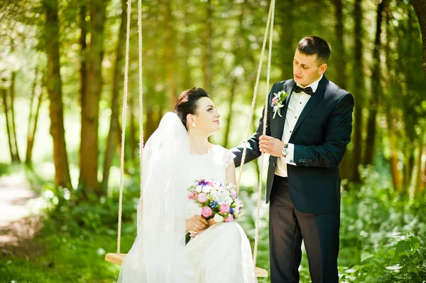 Recém-casados no balanço na madeira — Fotografia de Stock