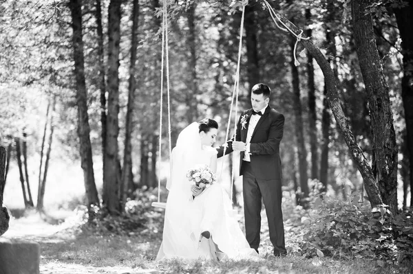 Recém-casados no balanço na madeira — Fotografia de Stock