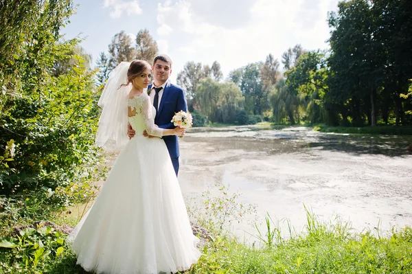 Wedding couple at the park near two stones and lake — Stock Photo, Image