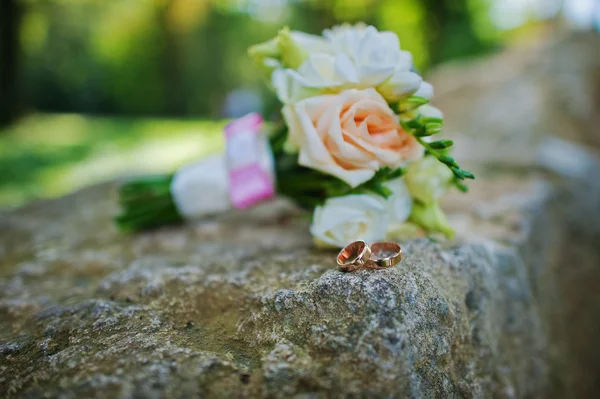 Wedding bouquet with rings on stone — Stock Photo, Image