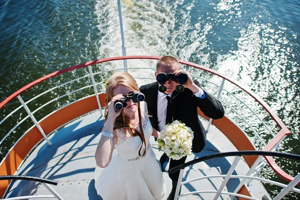 Casamento casal no navio olhando através binóculos — Fotografia de Stock