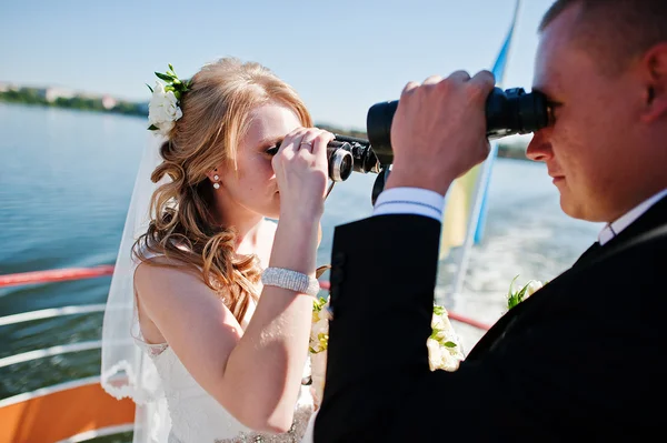 Wedding couple on ship looking through binoculars — Stock Photo, Image