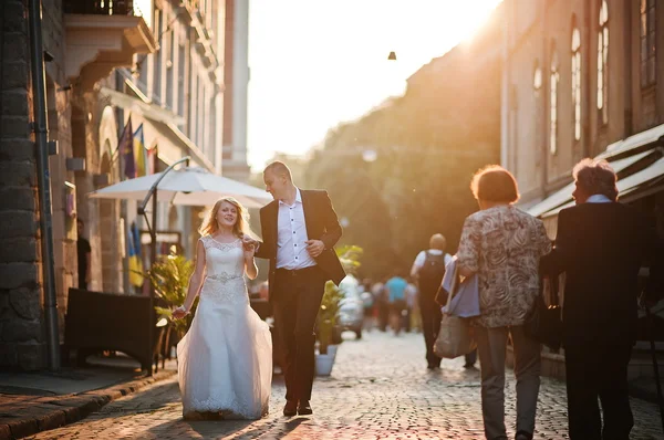 Весільна пара гуляє по вулицях міста на заході сонця — стокове фото