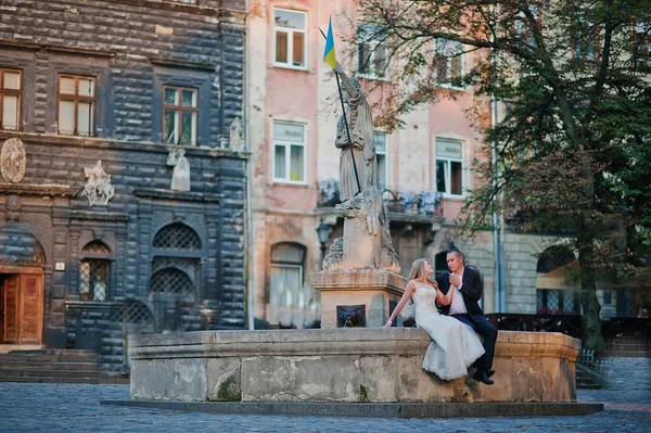 Couple de mariage assis sur le monument le plus ancien de la ville Lviv — Photo