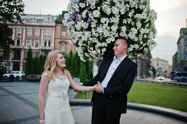 Casal de casamento andando nas ruas de flores de fundo da cidade — Fotografia de Stock