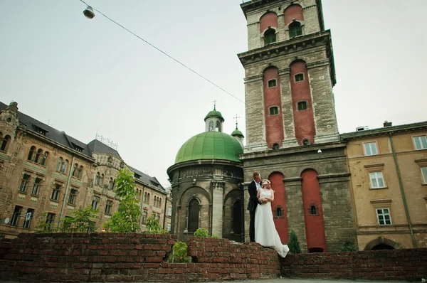 Hochzeitspaar spaziert auf Straßen der Stadt im Hintergrund alter Turm — Stockfoto
