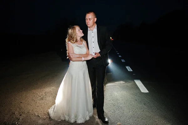 ライト車の夜の道路の背景に新婚夫婦 — ストック写真